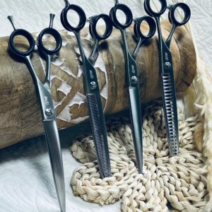Five black hairdressing scissors on woven mat