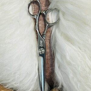 Polished silver haircutting scissors on white fur