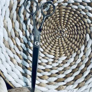 Black hairdressing scissors on woven round mat