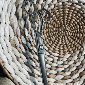 Silver hairdressing scissors on woven placemat